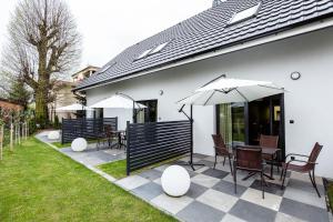 a patio with tables and chairs and an umbrella at Apartamenty Caminski Deluxe in Kudowa-Zdrój