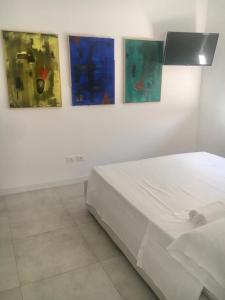 ein weißes Schlafzimmer mit drei Gemälden an der Wand in der Unterkunft Luxury villa Blue&Blanc piscina a sfioro isola in Diamante