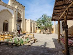 a courtyard with benches and a wheel in a building at madrasah Polvon-Qori boutique hotel XIX century in Khiva