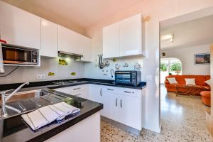a kitchen with white cabinets and a sink and a couch at Villas Guzman - Berg in Benissa