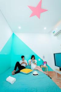 um homem e uma mulher sentados numa cama num quarto em Như Ngọc Motel em Cà Mau