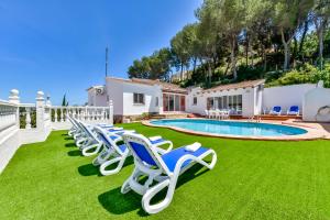 a row of chaise lounge chairs on a lawn next to a pool at Villas Guzman - Berg in Benissa