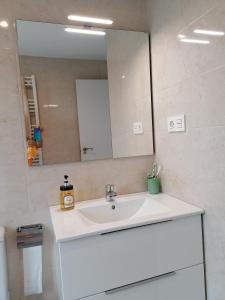 a bathroom with a white sink and a mirror at Luminoso Apartamento en Circulo Miramar in Luanco