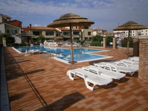 a pool with a bunch of lounge chairs and umbrellas at Residence Garbin - Agenzia Cocal in Caorle