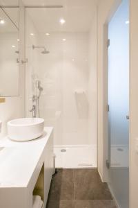 een witte badkamer met een wastafel en een douche bij Mercure Roeselare in Roeselare