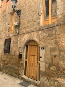 um antigo edifício de pedra com uma porta de madeira em Casa del Aire - Patio Apartment em Maella