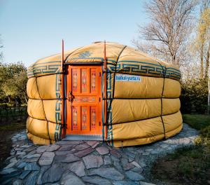 a large dome house with an orange door on top at Całoroczne jurty mongolskie - "Domy Słońca" in Kłodzko