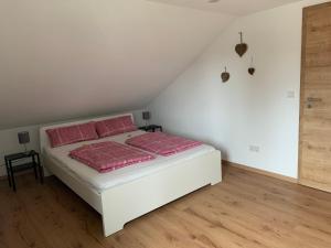 a white bed with pink pillows in a room at Ruhige Ferienwohnung nähe des Zentrums in Marktoberdorf
