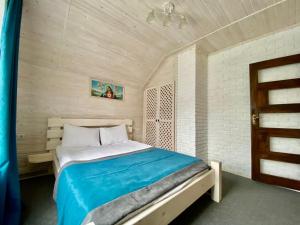 a bedroom with a bed with a blue blanket at Chalet Зоряні ночі in Mykulychyn