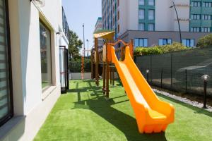 a playground with an orange slide on the grass at Hotel Duca Degli Abruzzi in Montesilvano