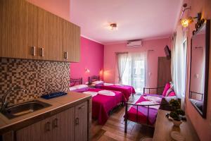 a kitchen with two beds in a room with pink walls at Christodoulos Eleftheria House in Nea Vrasna