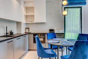 une cuisine avec une table et des chaises bleues dans une cuisine dans l'établissement Apartament BlueSun z ogródkiem Rezydencja Niechorze 128, à Niechorze