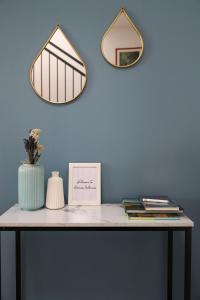 ラヴェンナにあるDomus Silvana Apartmentsの青い壁に鏡が2つあるテーブル