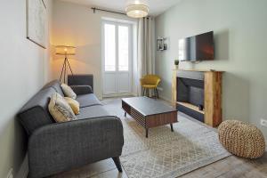 a living room with a couch and a tv at Centre-ville - Fibre - Netflix - T2 L'ISAC in Blain