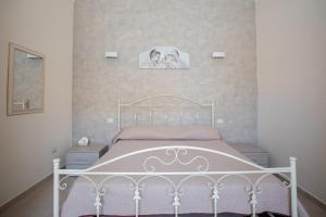 una camera con un letto bianco e una foto appesa al muro di Appartamento Bea a Torre Lapillo