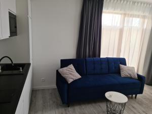 a blue couch in a living room with a window at COSTA Apartamenty w Sarbinowie in Sarbinowo