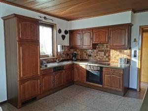 a large kitchen with wooden cabinets and a window at Ferienhaus Eifelmomente in Gerolstein