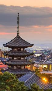 a large building with a tower in a city at Nara Deer Hostel- - 外国人向け - 日本人予約不可 in Nara