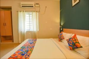 a bedroom with a large bed with a window at FabHotel Sasti Inn in Chennai