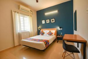 a blue bedroom with a bed and a desk and a desk at FabHotel Sasti Inn in Chennai