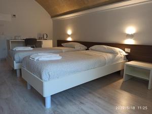 two beds in a room with two tables at In & Out Matera in Matera