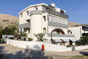 a white building with a hill in the background at Apartments Antonio in Pag