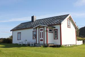 a small white house with a table and chairs at Hov Feriehus in Gimsøy