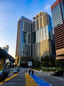 Un gruppo di persone che camminano per una strada di città con edifici alti di Happy Suite at Platinum KLCC a Kuala Lumpur