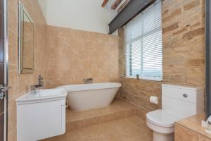 baño con bañera, aseo y ventana en Heritage Serviced Suites - Serviced Apartments, en Huddersfield