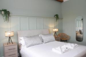 a bedroom with a white bed with two lamps and a mirror at Heritage Serviced Suites - Serviced Apartments in Huddersfield