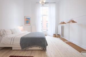 - une chambre blanche avec un lit et une grande fenêtre dans l'établissement Cosy and Modern 2 bedrooms flat near Châtelain and Brugmann, à Bruxelles
