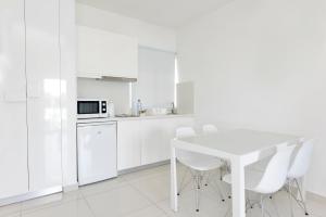 a white kitchen with a white table and white appliances at Mon Repos Hotel in Ayia Napa