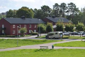 Ein Wohnwagen parkt auf einem Parkplatz neben einem roten Gebäude in der Unterkunft Slagsta Motell & Wärdshus in Norsborg
