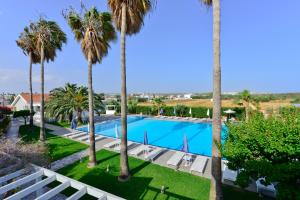 a view of the pool from the balcony of a resort with palm trees at Mon Repos Hotel in Ayia Napa