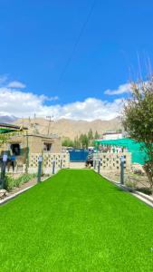 a yard of green grass in front of a building at Mangyul guest house in Leh