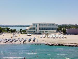 a beach with a large building and people in the water at Hotel Malibu in Mamaia