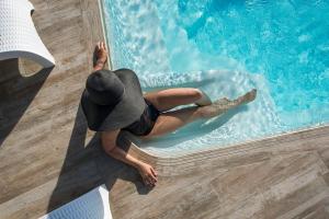 Uma mulher de chapéu está deitada numa piscina. em Oia Sunset Villas em Oia
