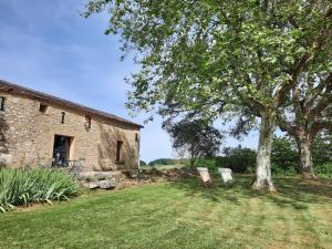 two chairs sitting under a tree next to a building at Domaine de la Borie Blanche- Pomport Monbazillac - Gîtes 1ch, 2ch et 3ch in Pomport