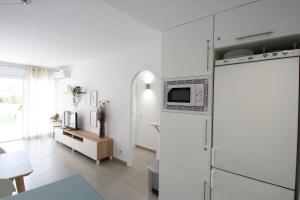 a white kitchen with a refrigerator and a table at Los Pelicanos in Miami Platja