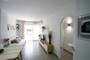 a white living room with a couch and a tv at Los Pelicanos in Miami Platja