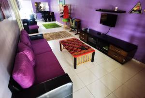 マラッカにあるHOMESTAY TERATAKMUSLIM KHAIRUL&ROZAINI Melakaのリビングルーム(紫色のソファ、テレビ付)