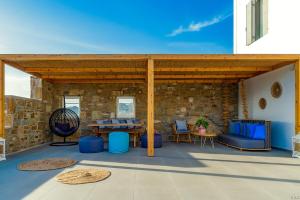 a patio with a wooden pavilion with a table and chairs at CASA DI PIETRA MYKONOS in Klouvas