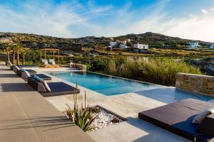 a swimming pool with lounge chairs in front of a mountain at CASA DI PIETRA MYKONOS in Klouvas