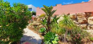 a garden with palm trees and a rock wall at Villa Cabanas beach in Budens
