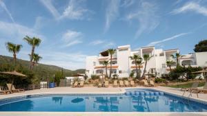 a resort with a swimming pool and palm trees at Apartamentos Blanco Sol in Cala Vadella