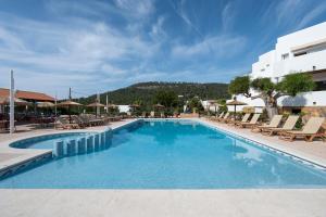 a large swimming pool with chairs and a building at Apartamentos Blanco Sol in Cala Vadella