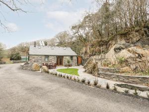 a stone cottage with a gravel road in front of it at Tyn Llwyn Cornel Eco Barn in Penrhyndeudreath