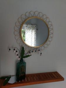 a mirror on a wall with a vase on a shelf at Ilmastoitu kesämökki Askolassa lähellä Porvoota in Askola