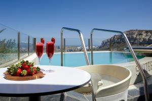 una mesa con dos copas de vino y un tazón de fresas en Suites of the Gods Cave Spa Hotel, en Megalokori
