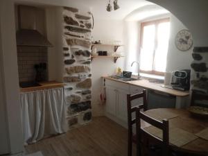 kuchnia ze stołem i kamienną ścianą w obiekcie Charmant Studio dans l’Ancienne Mairie w mieście Saint-Laurent-le-Minier